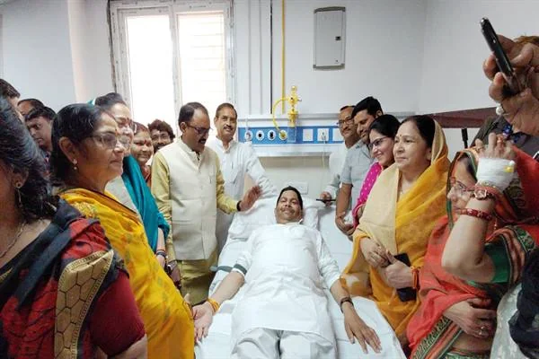 अस्पताल के बिस्तर पर रक्तदान करते व्यक्ति के आसपास खड़े जनप्रतिनिधि और अन्य लोग